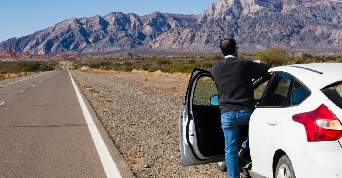 Tourist driving a rental car in Morocco through scenic desert road