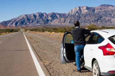 Tourist driving a rental car in Morocco through scenic desert road